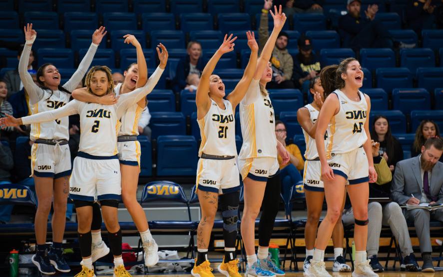 Group of women's basketball players celebrate on the basketball court during a game.